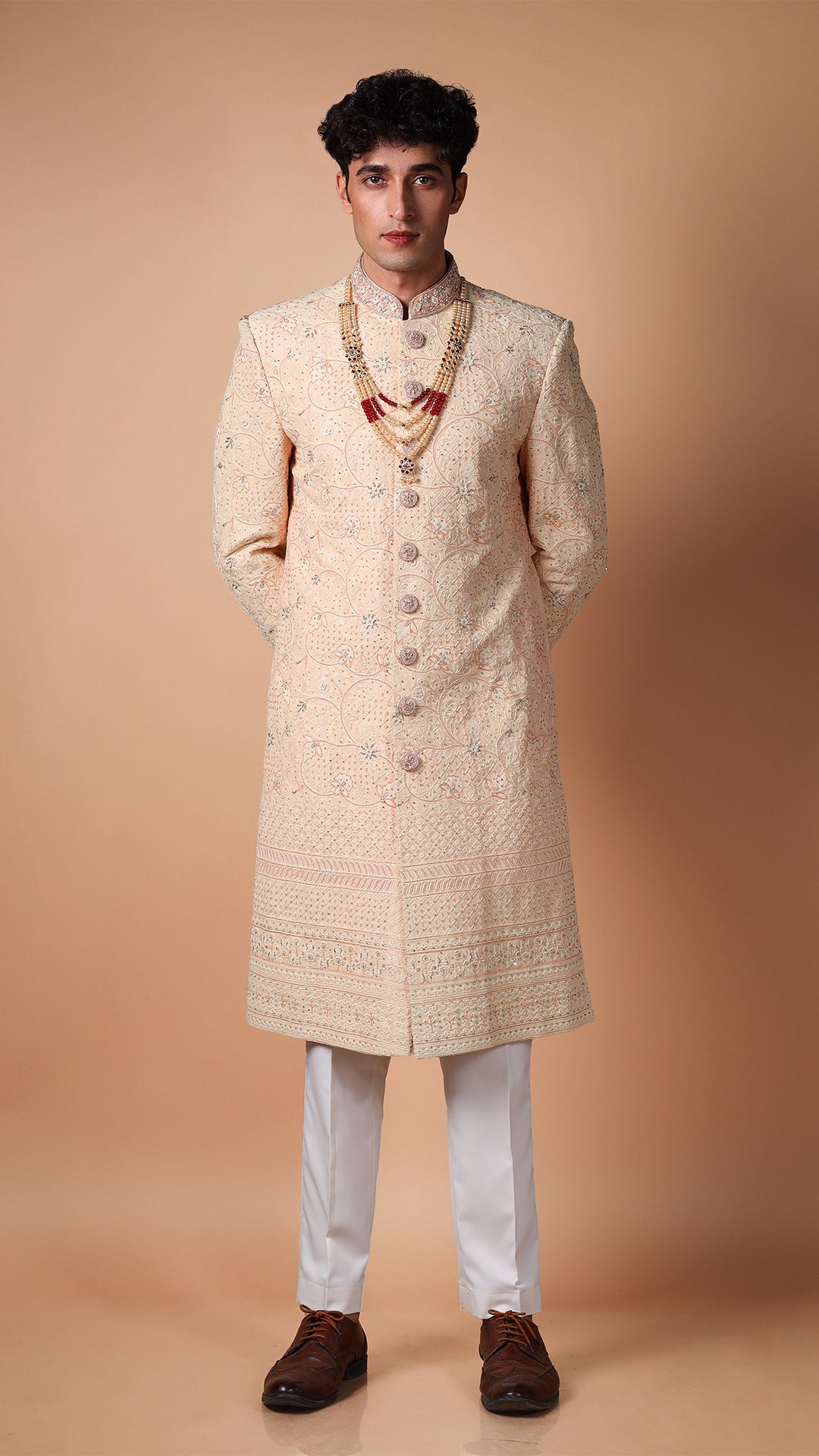 Peach Lucknowi Hand Embroidered Sherwani, emphasizing the intricate patterns of the embroidery. The smooth and luxurious fabric drapes elegantly.