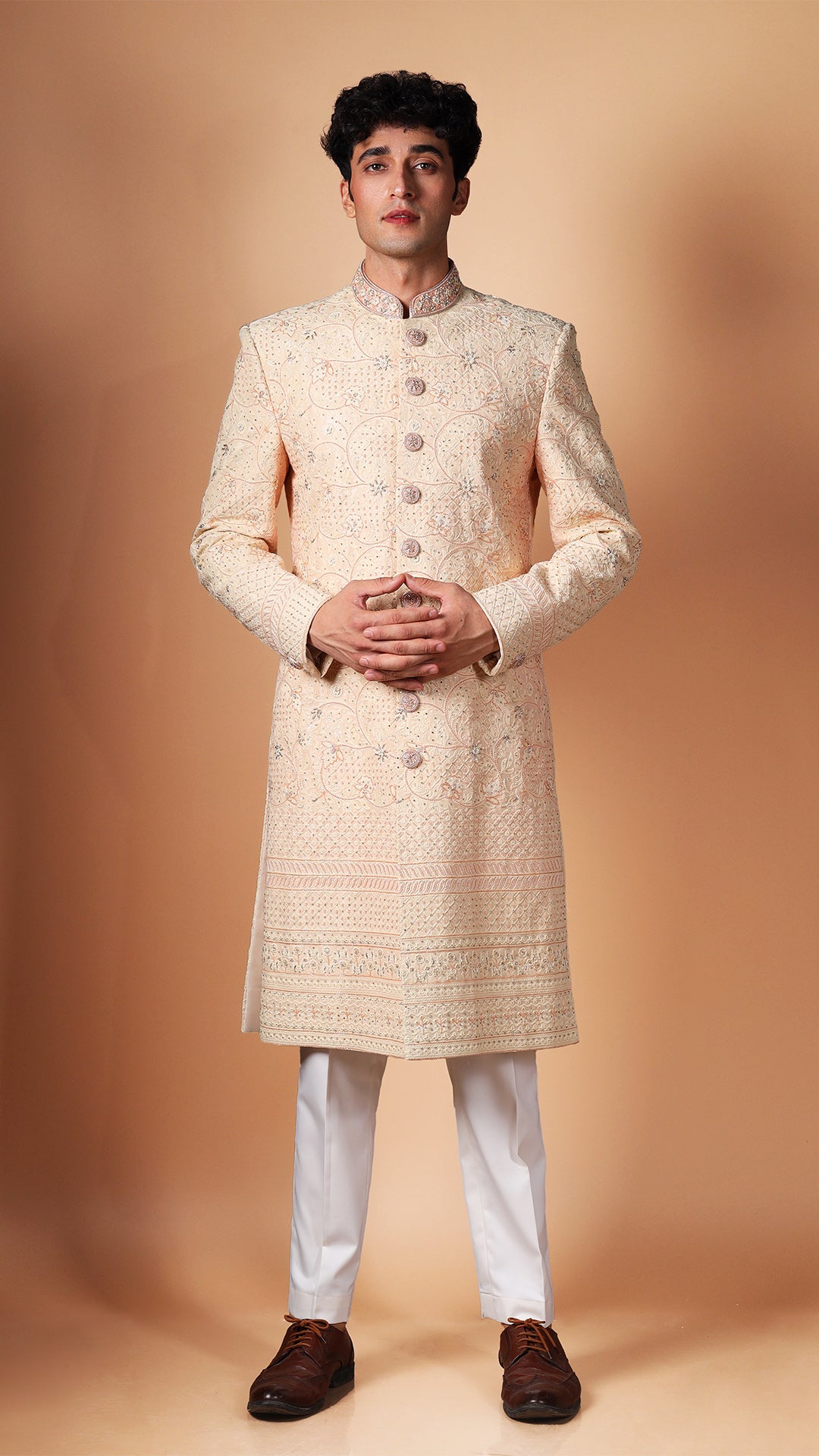 showcasing the detailed Lucknowi embroidery on the Peach Sherwani. The off-white bottoms complement the peach color, adding to the ensemble's elegance.